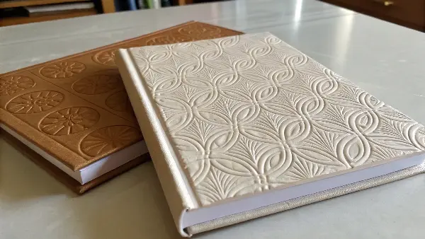 A side-by-side comparison showing an embossed logo and a debossed logo on thick paper.