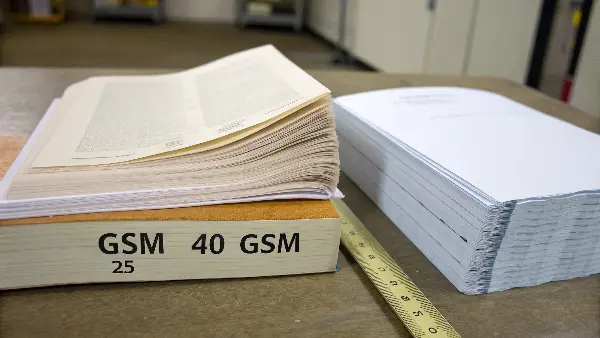 A digital scale showing the low weight of a sheet of Bible paper.